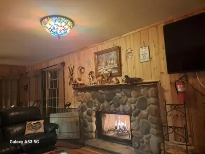 a living room with a stone fireplace and a television at 4BR ski on ski off Hunter Mountain Highlands Condo in Hunter