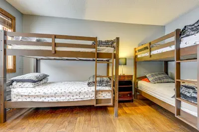 two bunk beds in a room with wooden floors at Less Than 1 Mi to Mt Snow Charming Condo with Fireplace in Dover
