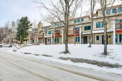 a building on a snow covered street with trees at Less Than 1 Mi to Mt Snow Charming Condo with Fireplace in Dover