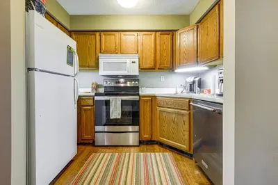 a kitchen with wooden cabinets and a white refrigerator at Less Than 1 Mi to Mt Snow Charming Condo with Fireplace in Dover