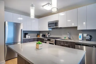 a kitchen with white cabinets and a large white counter top at Modern Apt Downtown in Stamford