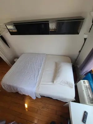 a bed in a room with white sheets and pillows at Nice rooms Woodside in Queens