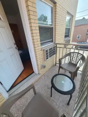 a balcony with a chair and a table and a door at Nice rooms Woodside in Queens