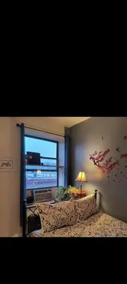 a bedroom with a bed and a window with a television at My apartment in New York