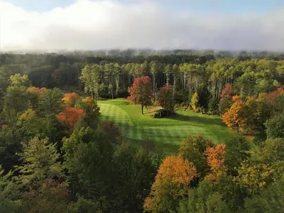an aerial view of a golf course in the forest at The Inn at Crumpin-Fox in Bernardston