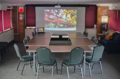 a conference room with tables and chairs and a projection screen at The Inn at Crumpin-Fox in Bernardston