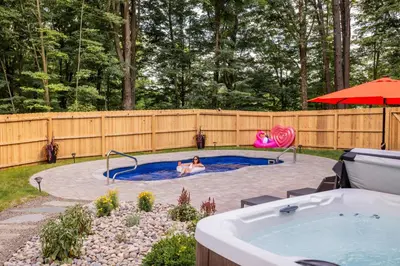 a woman swimming in a pool with a hot tub at Sauger home in Saugerties