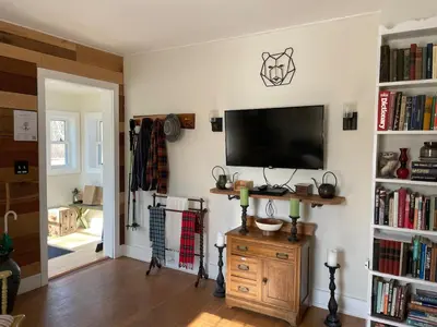 a living room with a flat screen tv on a wall at Pleasant Brook Cottage in Roxbury