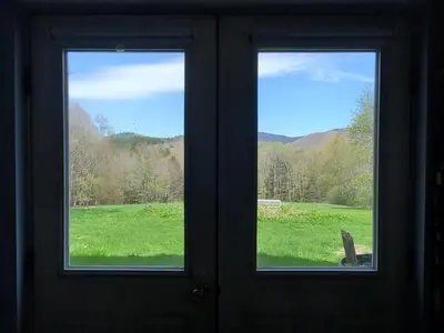 a door with two windows with a view of a field at Pleasant Brook Cottage in Roxbury