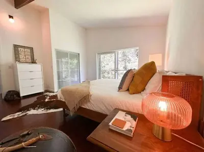 a bedroom with a bed and a table with a lamp at Unique and Private 25ft Waterfall House in Hunter in Elka Park