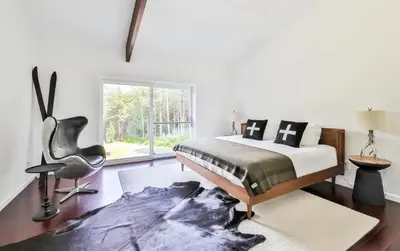 a bedroom with a bed and a chair and a window at Unique and Private 25ft Waterfall House in Hunter in Elka Park