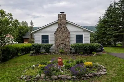 a house with a fire hydrant in a flower garden at Hunter Mountain View Cabin in Lanesville