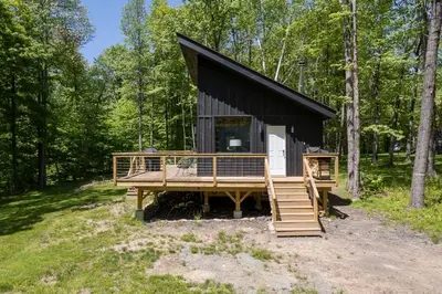 a cabin in the woods with a large deck at Modern Rustic Tiny Home in the Catskills in Roscoe