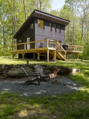 a cabin in the woods with a deck and a bench at Modern Rustic Tiny Home in the Catskills in Roscoe