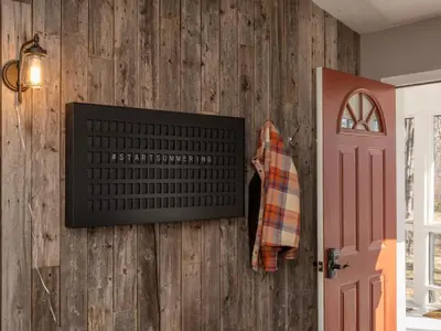 a room with a wooden wall with a tv and a door at Private Cabin with Guesthouse Hot Tub Fire Pits in Roscoe