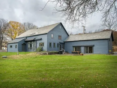 a blue house on a field with a grass yard at Chic Barn House with Pool in Germantown