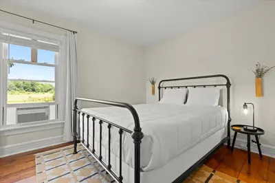 a white bedroom with a bed and a window at Hudson Restored Farmhouse with Fire Pit in Hudson