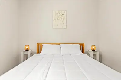a bedroom with a large white bed with two candles at Hudson Restored Farmhouse with Fire Pit in Hudson