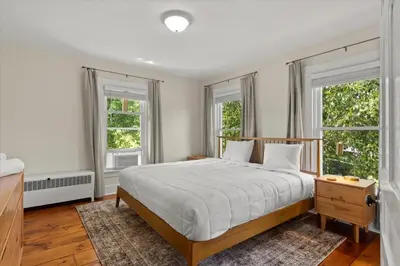 a bedroom with a large bed and two windows at Hudson Restored Farmhouse with Fire Pit in Hudson