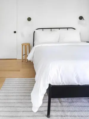 a bedroom with a bed with white sheets and a rug at Private Cabin by River with Fireplace in Phoenicia