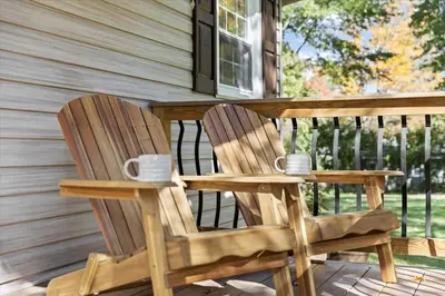 two wooden chairs sitting on the porch of a house at Cozy Home with Game Room and Fire Pit in New Paltz