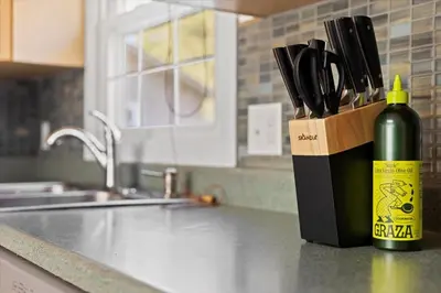 a bottle of wine sitting on a counter next to a knife block at Cozy Home with Game Room and Fire Pit in New Paltz