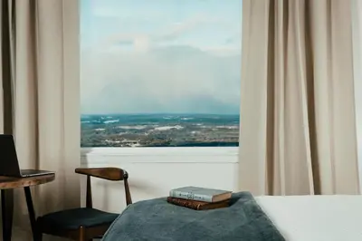 a bedroom with a bed and a chair and a window at The Perch Hotel in East Windham