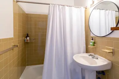 a bathroom with a white shower curtain and a sink at The Perch Hotel in East Windham