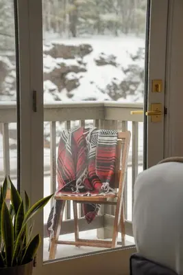 a chair with a pillow on a balcony with a window at The Perch Hotel in East Windham