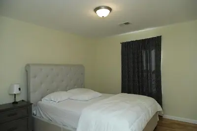 a bedroom with a bed with white sheets and a window at Spacious 3 Bedroom, 15 Min to EWR Airport and Parks in Newark