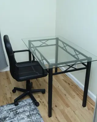 a glass table with a black chair and a glass desk at Spacious 3 Bedroom, 15 Min to EWR Airport and Parks in Newark