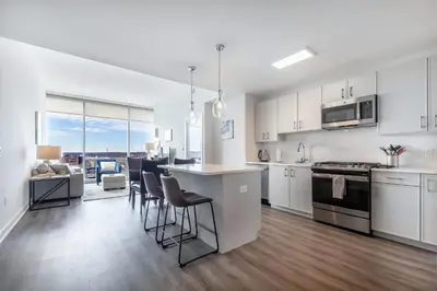 a kitchen with white cabinets and a kitchen island with chairs at Luxury 2 BR Apt with Gym in Stamford
