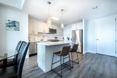 a kitchen with a bar and chairs and a table at Luxury 2 BR Apt with Gym in Stamford