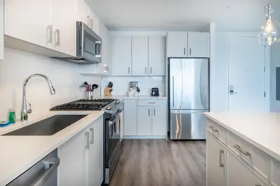 a kitchen with white cabinets and a stainless steel refrigerator at Luxury 2 BR Apt with Gym in Stamford
