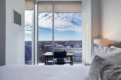 a bedroom with a bed and a desk and a large window at Luxury 2 BR Apt with Gym in Stamford