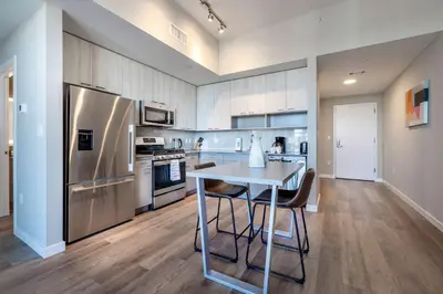 a kitchen with a table and a stainless steel refrigerator at Spacious Harbor Apt with Balcony in South End