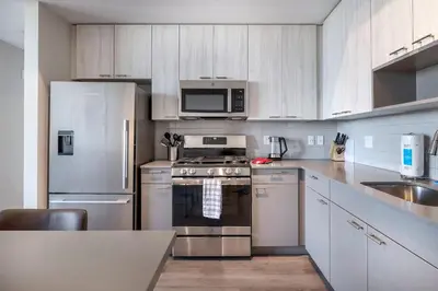 a kitchen with stainless steel appliances and white cabinets at Spacious Harbor Apt with Balcony in South End