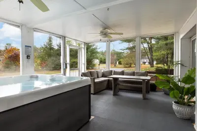 a large living room with a tub and a couch at 3BR Lake Luzerne Retreat with Game Room & Cozy Fire Pit in Lake Luzerne