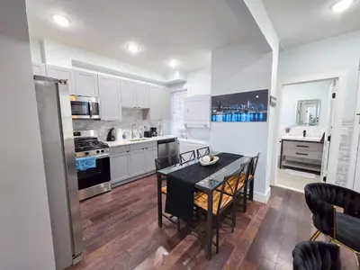 a kitchen with white cabinets and a table and chairs at Cozy apartment near New York City in Jersey City