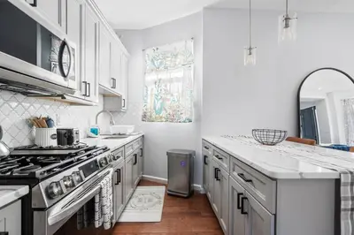 a kitchen with white cabinets and a stove top oven at Modern 3 Bed Apt Parking W D in Schenectady