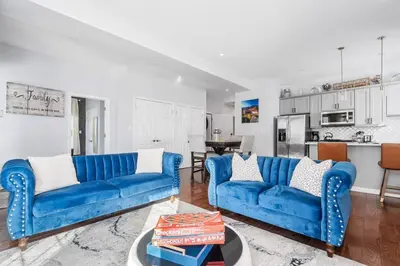 a living room with two blue couches and a kitchen at Modern 3 Bed Apt Parking W D in Schenectady