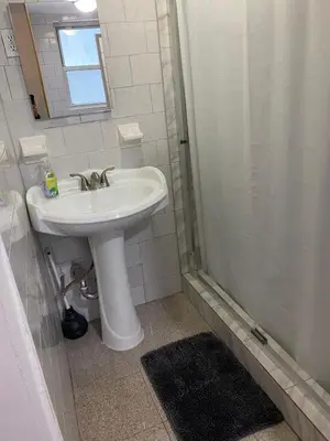 a white bathroom with a sink and a shower at Prime Murray Hill 2 BR Gem in New York
