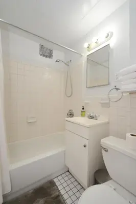 a white bathroom with a tub and a sink and a toilet at Prime Murray Hill 1BR - Near Grand Central in New York