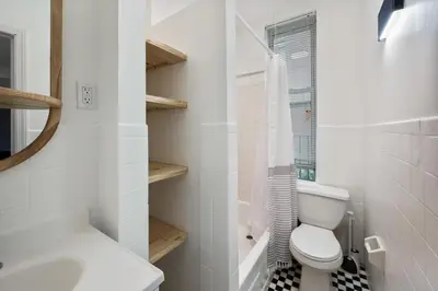 a white bathroom with a toilet and a sink at Spacious 2BR on the Upper East Side Steps from Central Park in New York