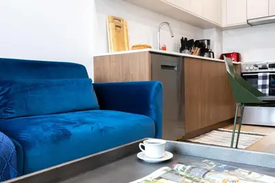 a living room with a blue couch and a kitchen at 149BK-302 New Construction 1BR WD in unit Balcony in Brooklyn
