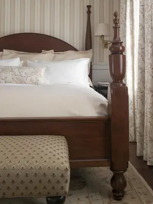 a bedroom with a bed with a wooden frame and a ottoman at The White Hart in Salisbury