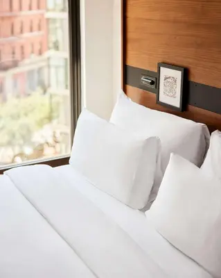 a bed with white pillows next to a window at Arlo SoHo in New York