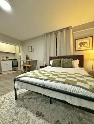 a bedroom with a large bed and a kitchen at Yale Casa Rosa Studio in New Haven