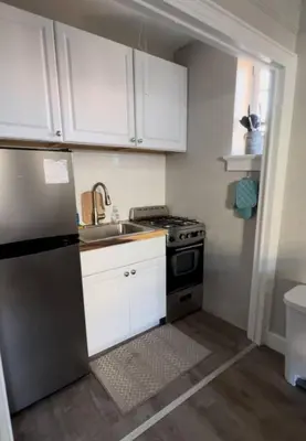 a kitchen with white cabinets and a stainless steel refrigerator at Yale Casa Rosa Studio in New Haven