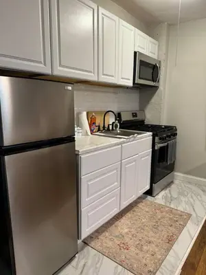 a kitchen with white cabinets and a stainless steel refrigerator at Yale Casa Verde Studio in New Haven